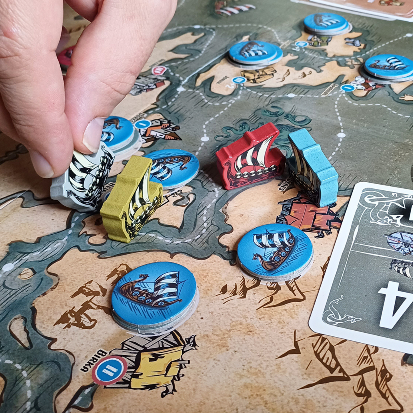 Nærbilde av Vikings Tales spillkomponenter med verdenskart spillebrett, kort, brikker og mynter