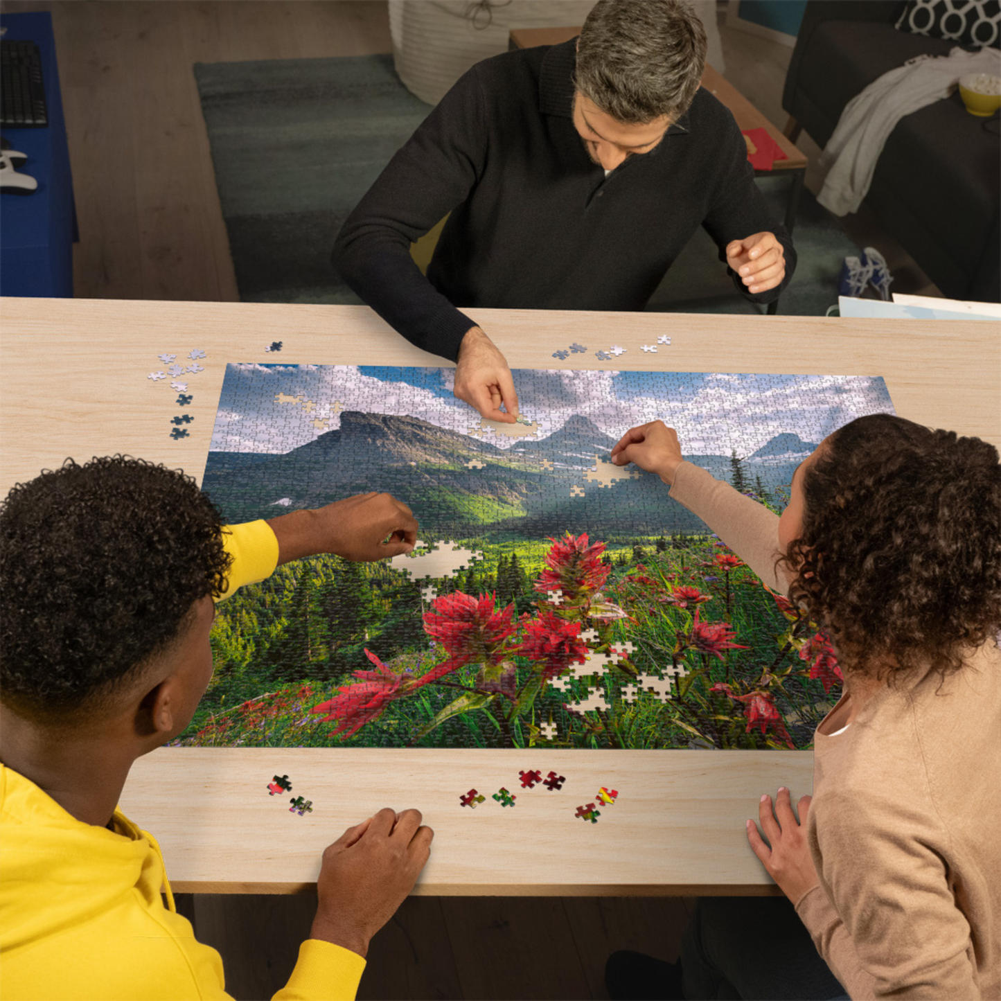 Personer pusler Ravensburger puslespill ved trebord med puslespillbrikker spredt rundt
