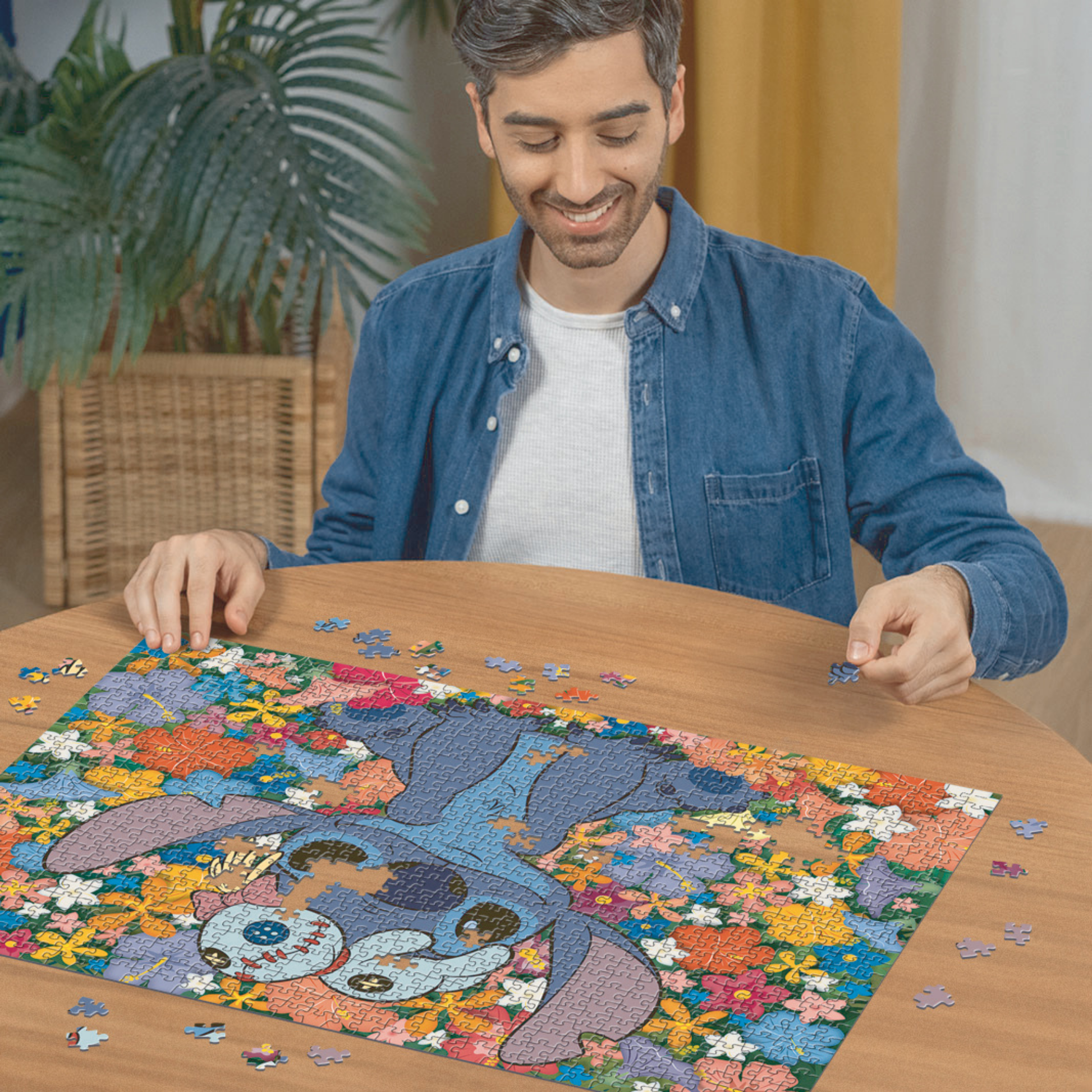 Person pusler Ravensburger puslespill ved trebord med puslespillbrikker spredt rundt