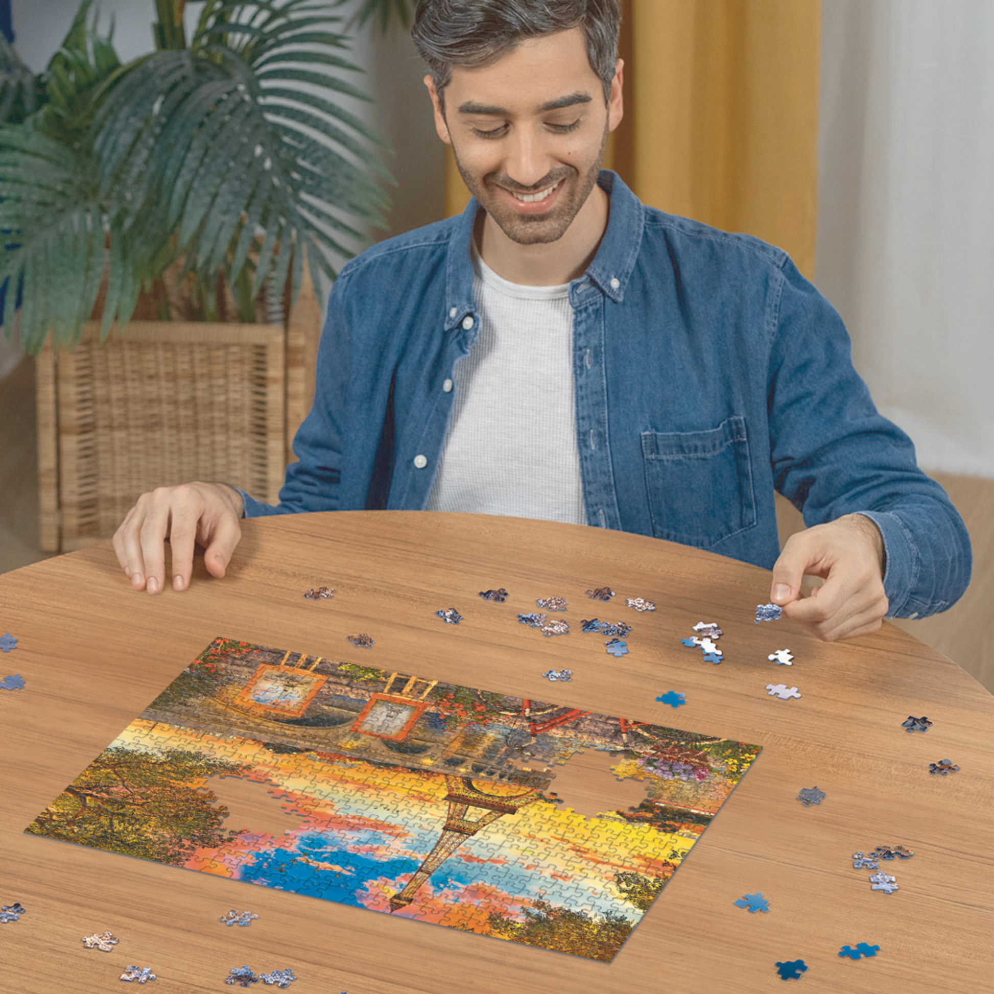 Person pusler Ravensburger puslespill ved trebord med puslespillbrikker spredt rundt