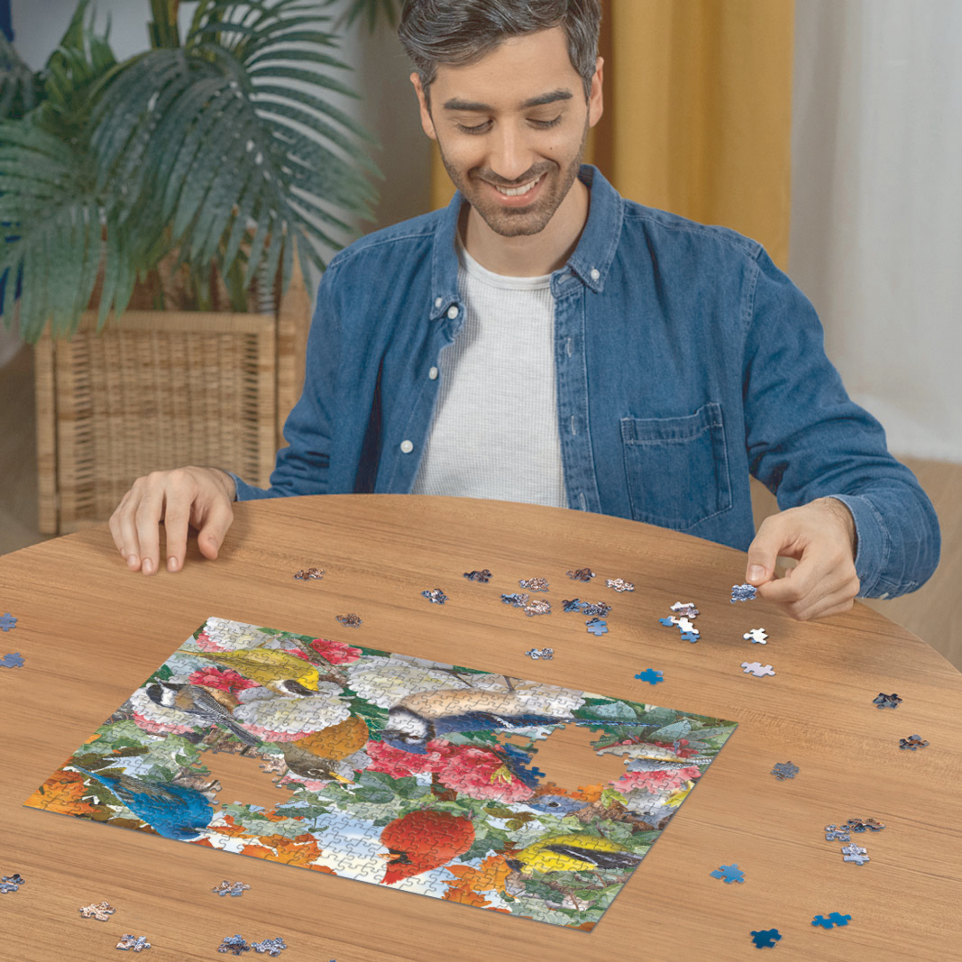 Person pusler Ravensburger puslespill ved trebord med puslespillbrikker spredt rundt