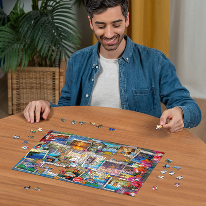Person pusler Ravensburger puslespill ved trebord med puslespillbrikker spredt rundt